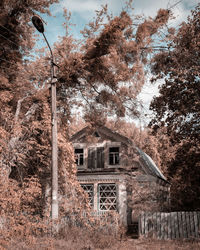 Old building by trees against sky