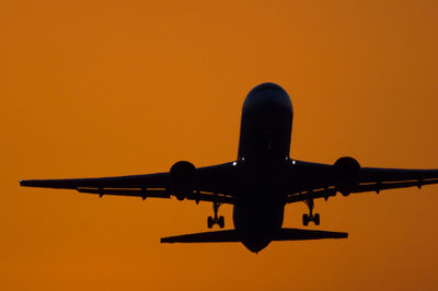 Low angle view of airplane against orange sky