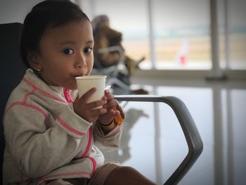 Portrait of young woman drinking coffee at home