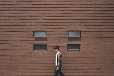 Man walking by wooden wall of house