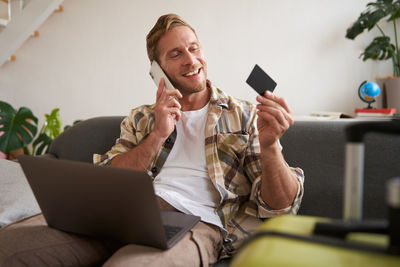 Young woman using phone while sitting on sofa at home