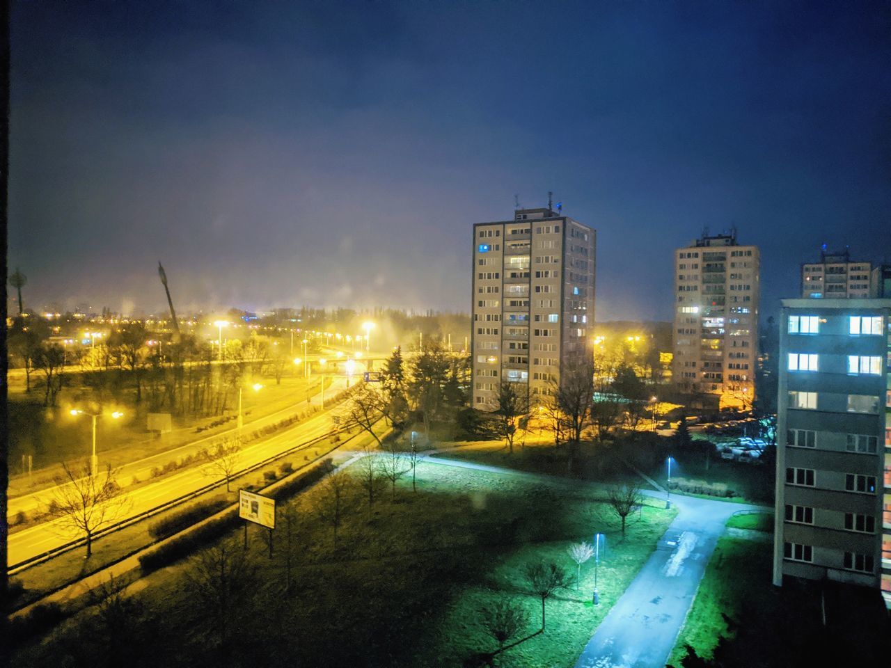 HIGH ANGLE VIEW OF ILLUMINATED CITY STREET AND BUILDINGS AT NIGHT