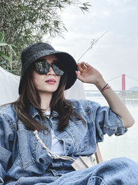 Portrait of young woman wearing sunglasses sitting outdoors