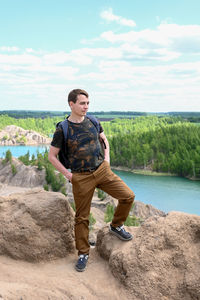 Rear view of man standing on rock against sky