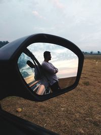 Reflection of man on side-view mirror