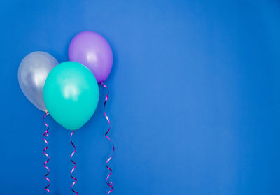 Low angle view of balloons against blue background