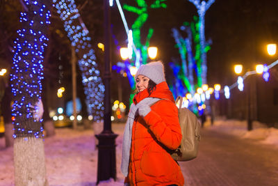 Person standing by illuminated christmas lights during winter at night