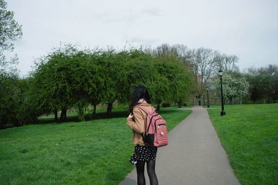 Rear view of woman standing by trees against sky