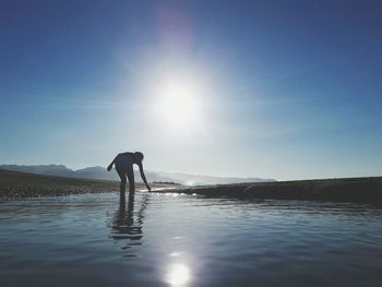 Woman standing in sea against blue sky