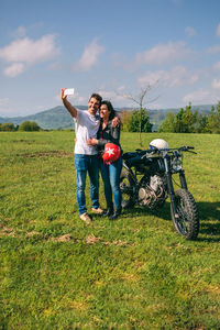 Young couple taking selfie against sky