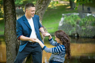 Man holding hands of woman while standing against lake