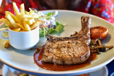 High angle view of meat and fries in plate on table