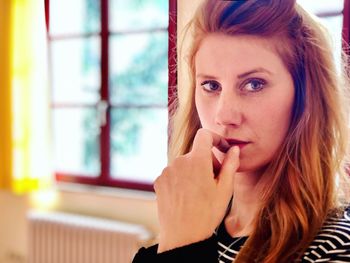 Portrait of young woman against window