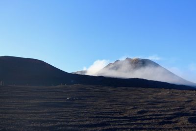 Scenic view of volcanic mountain against blue sky