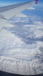 Aerial view of airplane wing over snow covered landscape