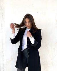 Portrait of young woman standing against wall