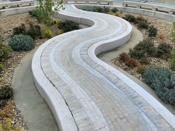 Curved fountain space amidst plants and trees in city