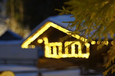 Low angle view of illuminated lighting equipment hanging at night