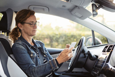 Mature woman texting while sitting in car