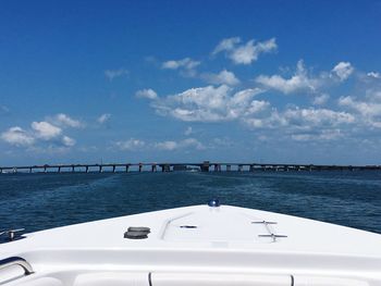 Boat sailing in sea by bridge against sky