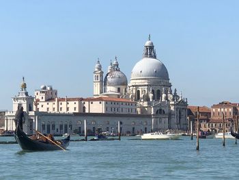 Boats in canal by buildings against clear sky