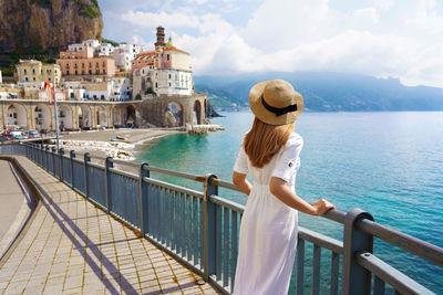 Back view of beautiful fashion girl enjoying view of atrani village on amalfi coast