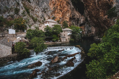 Scenic view of waterfall by rocks and trees