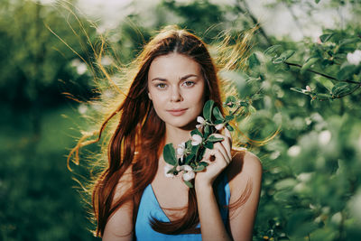 Portrait of young woman standing amidst plants