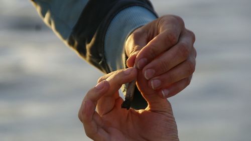 Cropped image of friends sharing cigarette