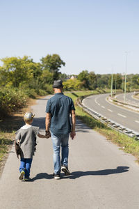 Rear view of father and son walking on road