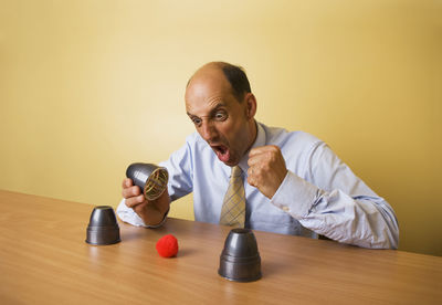 Portrait of man sitting on table against wall