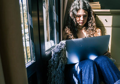 Young woman using phone while sitting at home