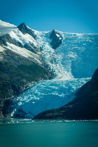 Scenic view of sea and snowcapped mountains against blue sky