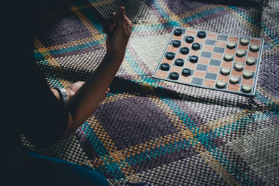 Cropped woman playing checkers on mat