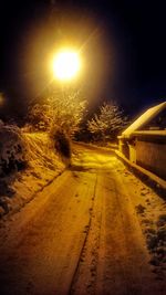 Road amidst illuminated trees against sky during sunset