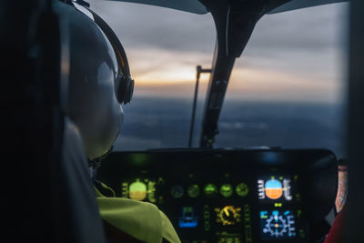 Pilot of helicopter emergency medical service flying over landscape at dusk. 