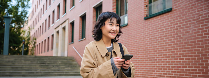 Portrait of young man standing against building