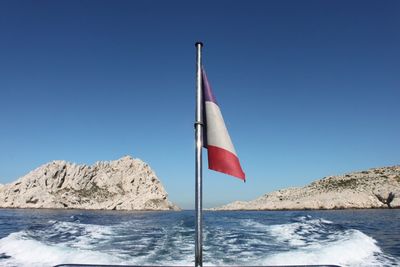 Flag on sea against clear blue sky