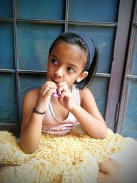 Close-up of girl eating chocolate against window