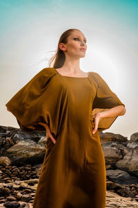 Portrait of young woman standing against sky