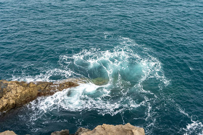 High angle view of waves splashing on rock