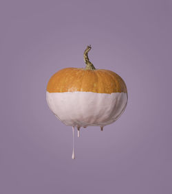 Decoration halloween. orange pumpkin, paint running down, minimalistic concept, purple background