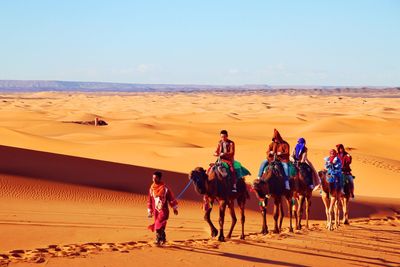 People riding horse in desert against sky