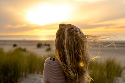 Rear view of woman with umbrella against sky during sunset