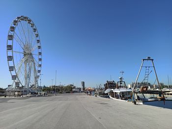Ferris wheel in city against clear blue sky