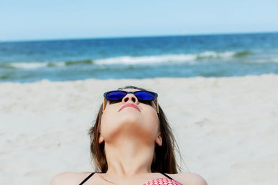 Woman wearing sunglasses at beach against sky