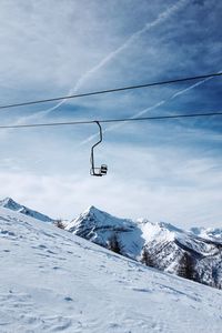Ski lift on snowcapped mountain against sky