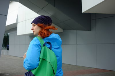 Side view of woman standing against wall