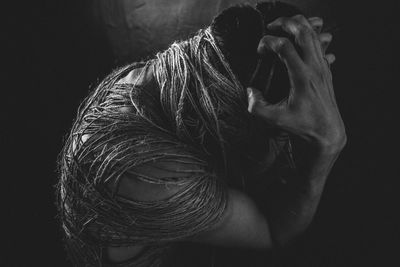 Close-up portrait of woman wearing mask against black background