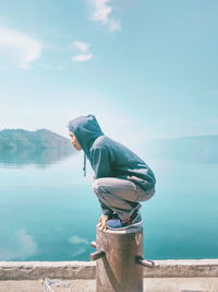 Side view of man standing by lake against sky